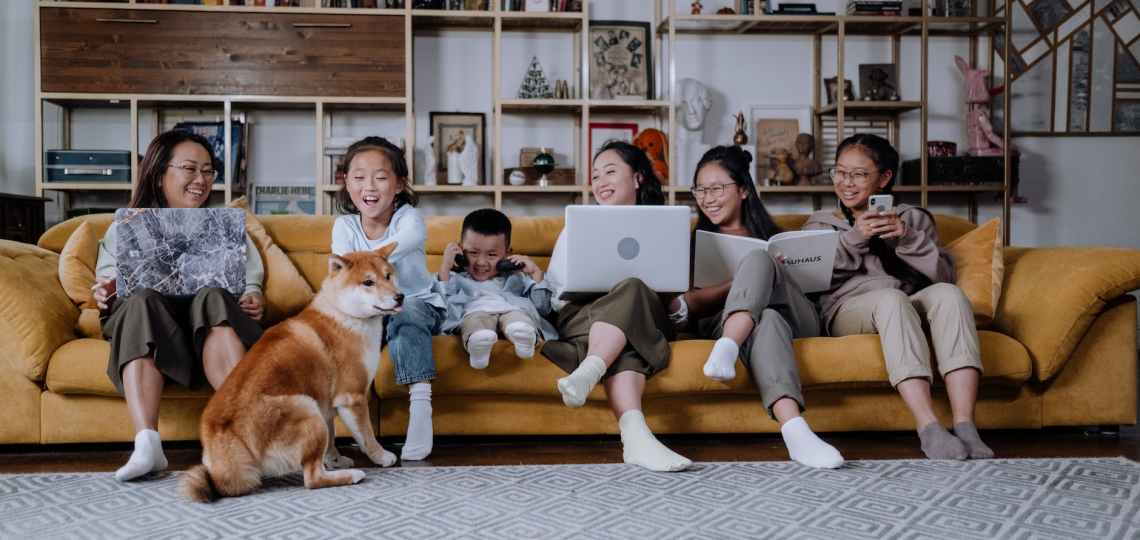 a happy family sitting on the couch while playing with their dog