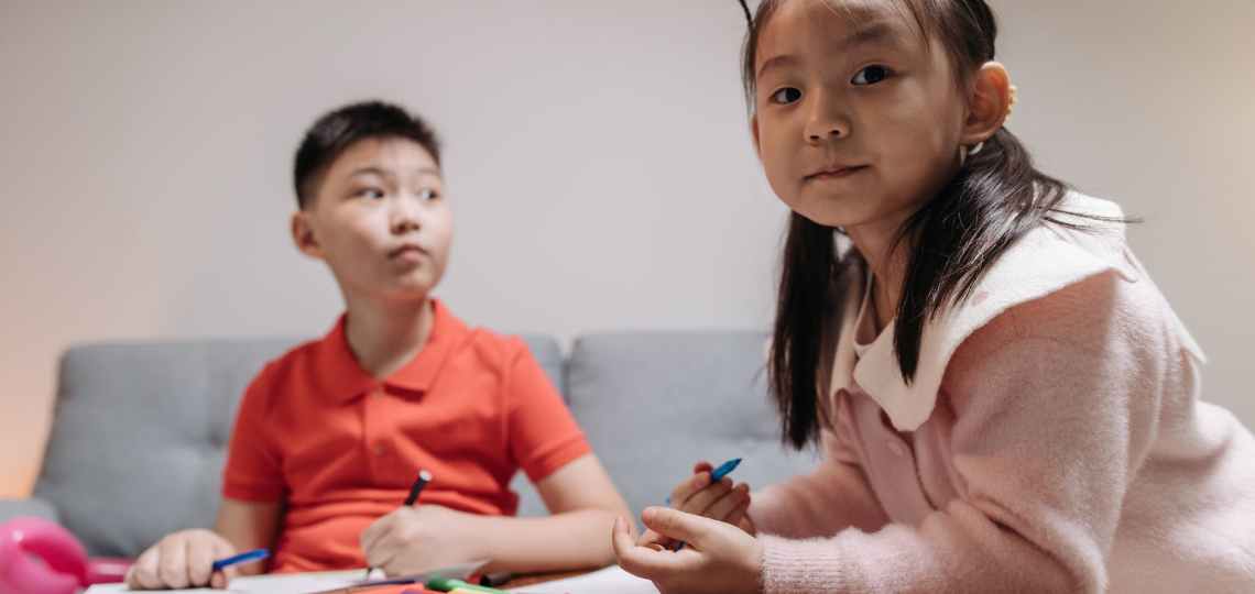 a young boy and girl holding a colored pens