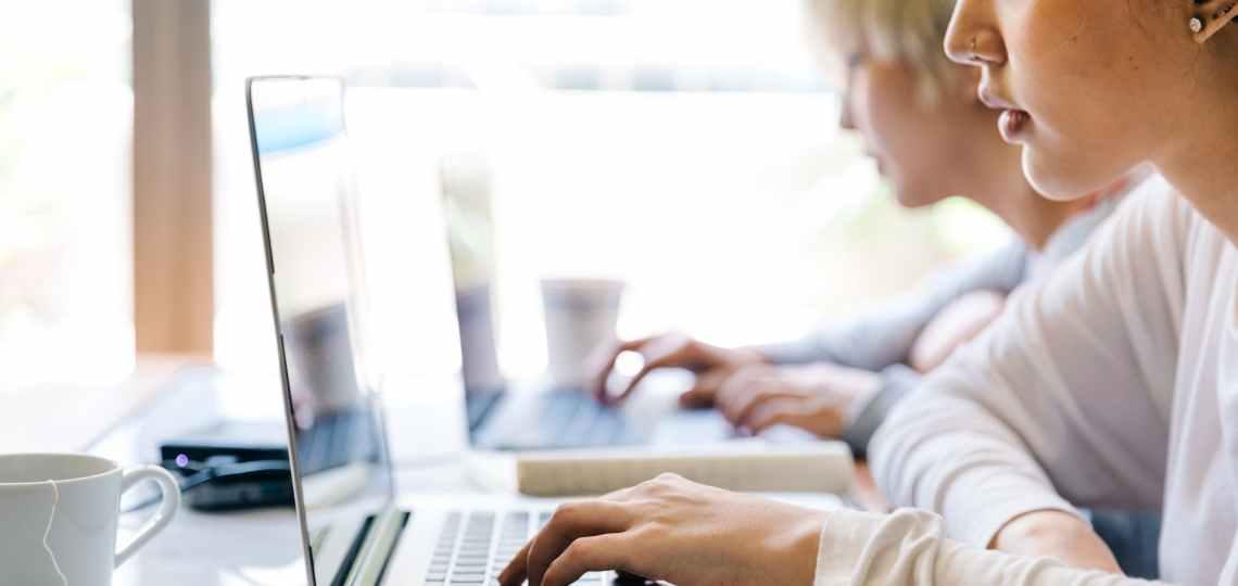 young women working on laptops in creative workspace