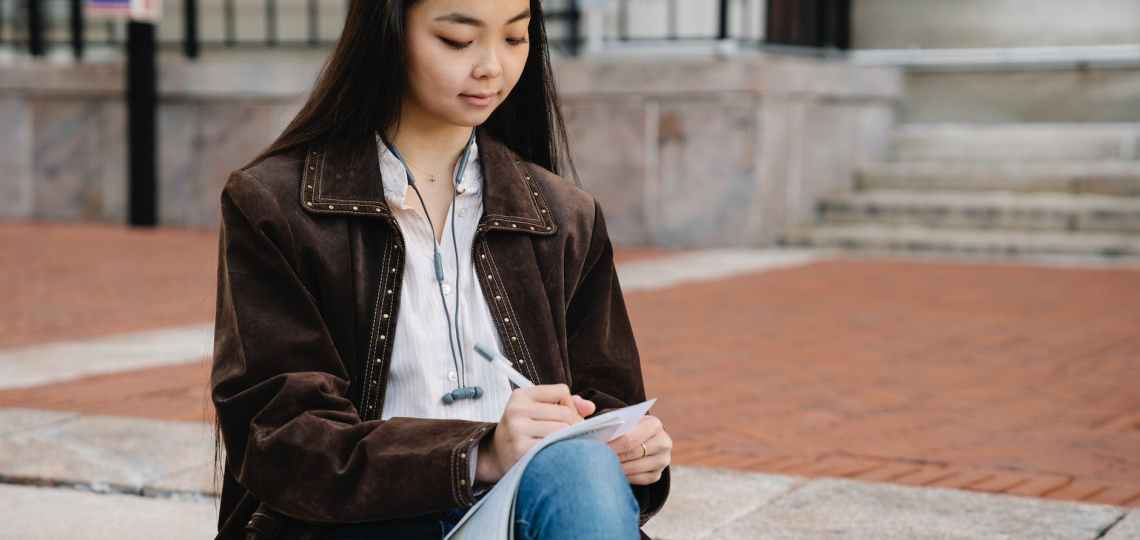 a woman studying while sitting on a concrete floor