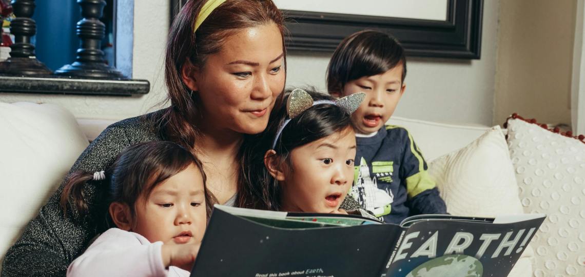 woman reading a book with her kids