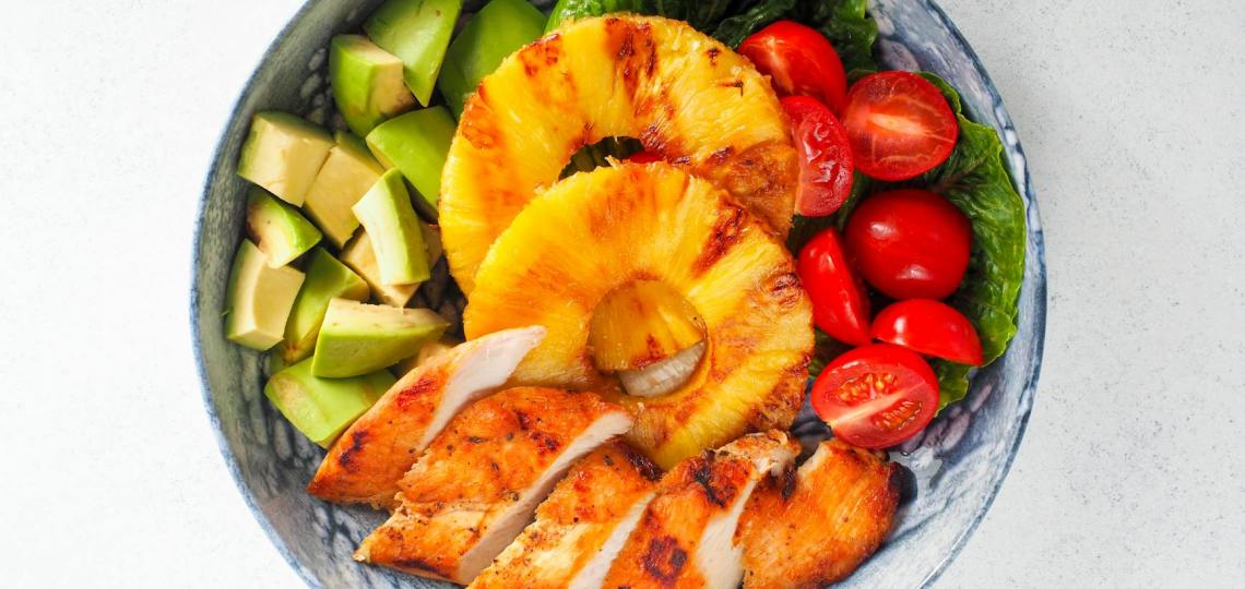 bowl of sliced fruits checken and chopped avocado