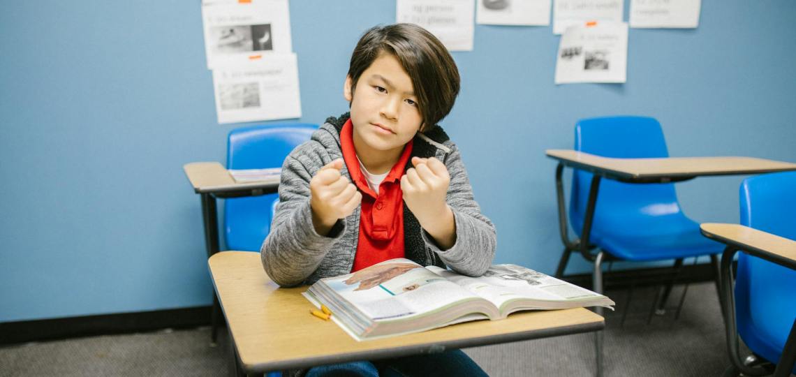 boy sitting on his desk looking angry