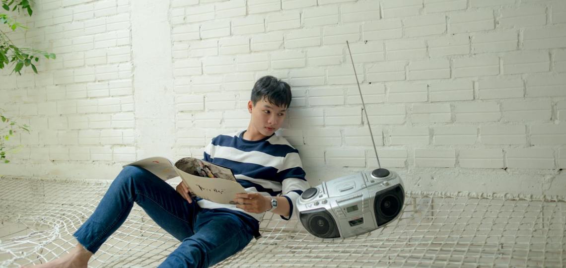 boy sitting near radio holding white catalog