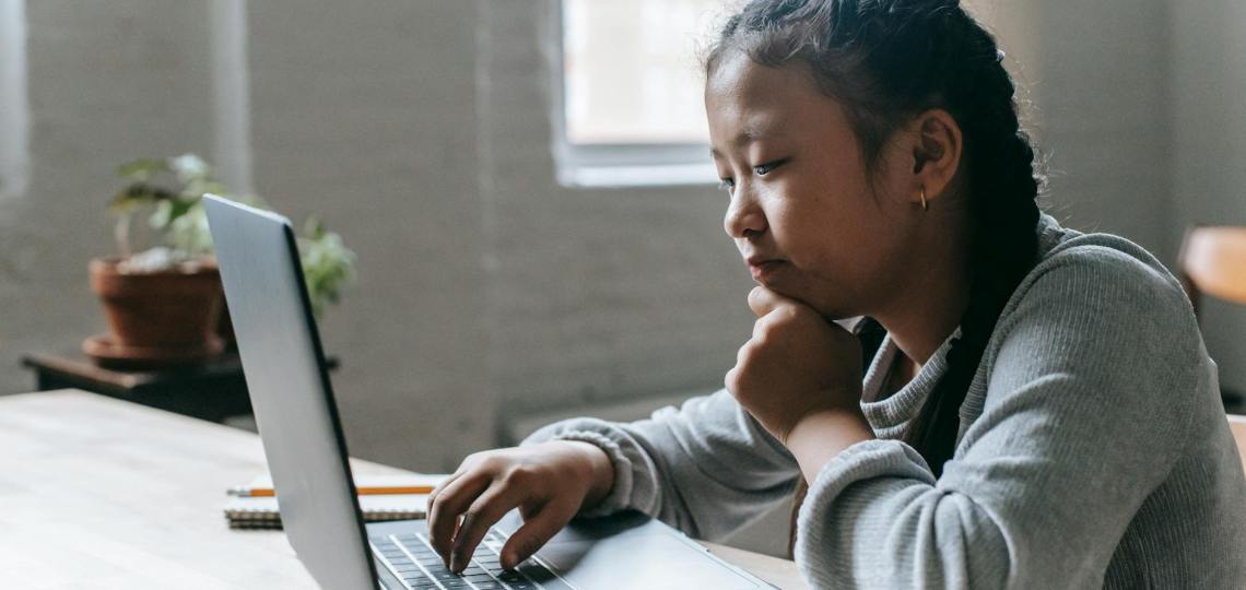 focused ethnic girl studying on laptop