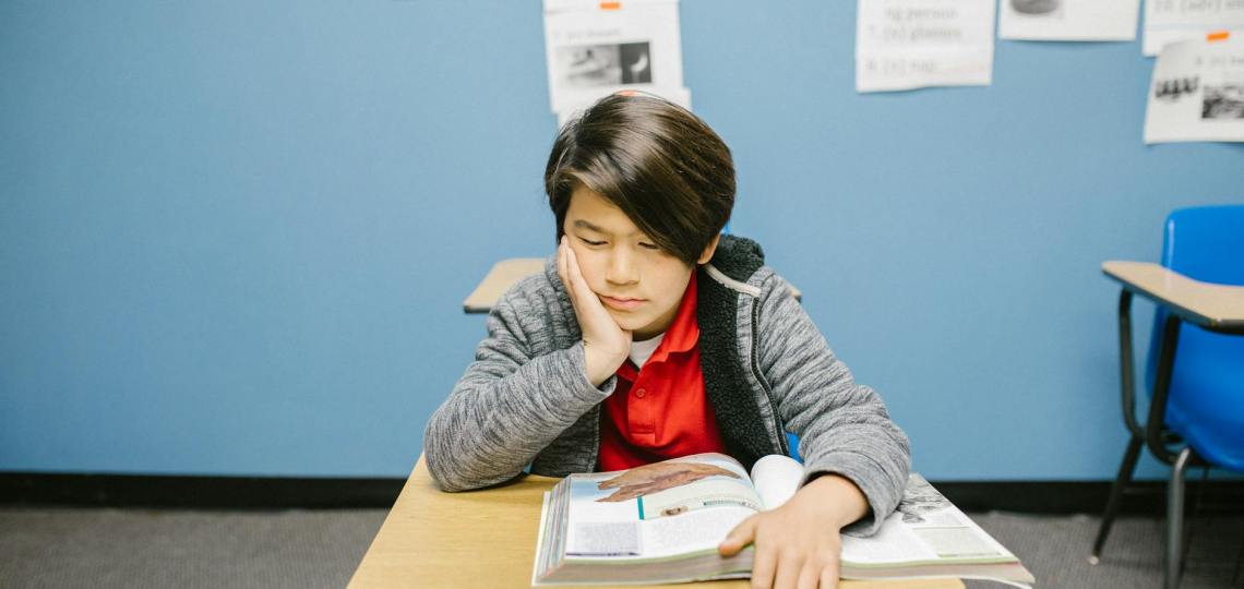 boy sitting on his desk looking lonely
